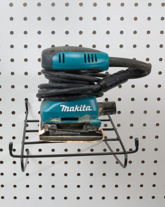 Sander hanging on angled pegboard hanger in garage workshop