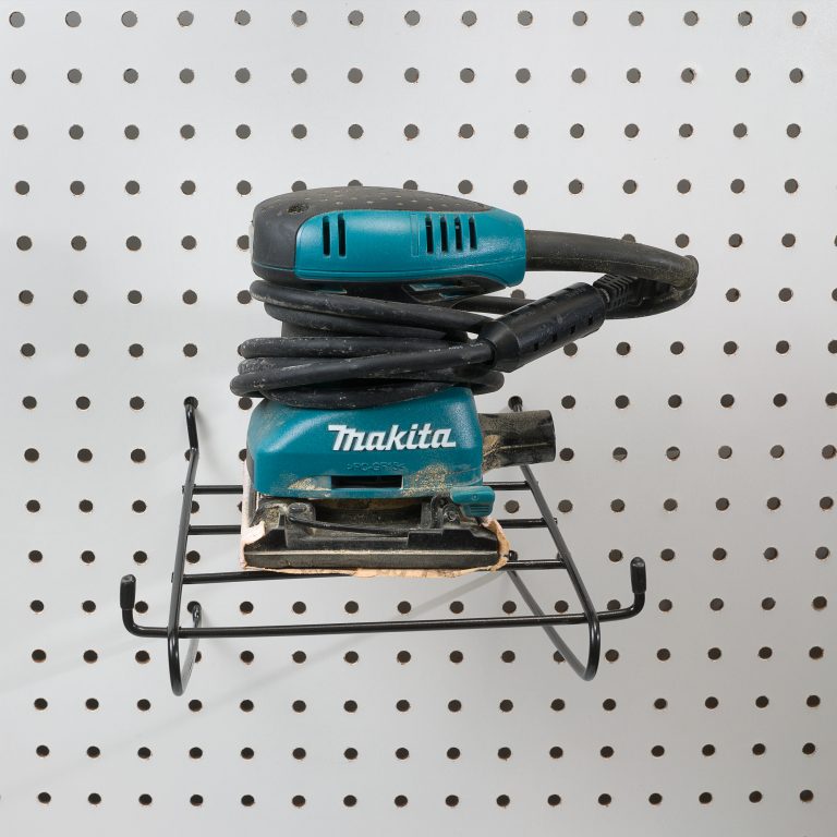 Sander hanging on angled pegboard hanger in garage workshop