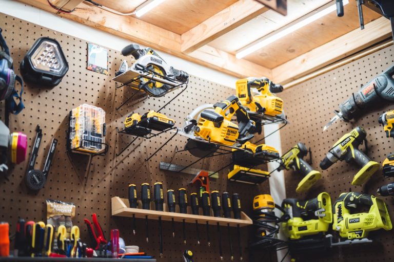 Garage pegboard wall organized with cordless power tools on metal hangers